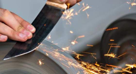 knife sharpening on a grind stone throwing sparks